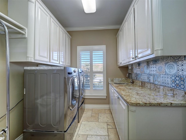 washroom featuring stone tile floors, a sink, ornamental molding, independent washer and dryer, and cabinet space