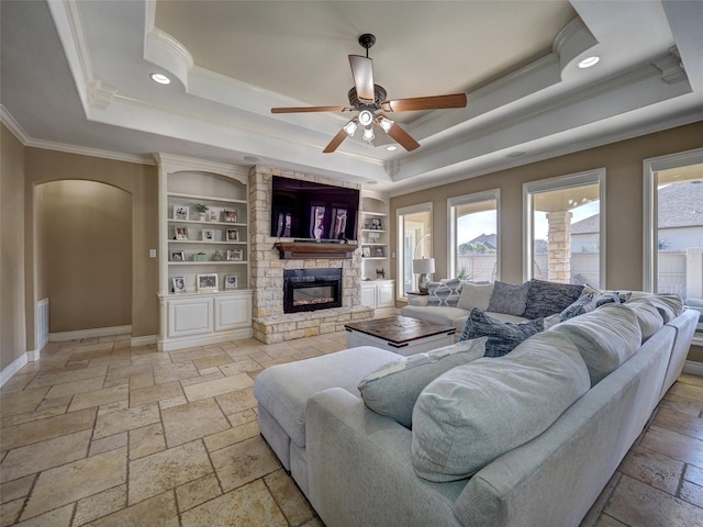 living room featuring a wealth of natural light, a raised ceiling, and stone tile flooring