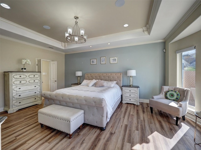 bedroom with light wood-style floors, a tray ceiling, a notable chandelier, and ornamental molding