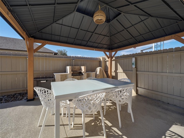 view of patio with outdoor dining space, a fenced backyard, an outdoor kitchen, and a gazebo