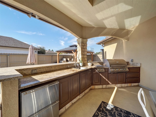 view of patio with a fenced backyard, area for grilling, a sink, a gazebo, and exterior kitchen