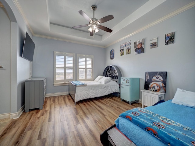 bedroom with a raised ceiling, ornamental molding, ceiling fan, wood finished floors, and baseboards