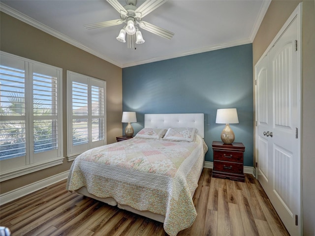 bedroom featuring light wood-type flooring, a ceiling fan, baseboards, and crown molding