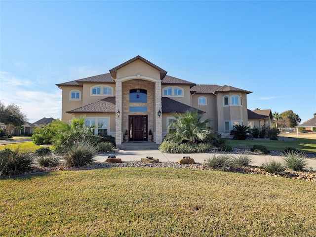 mediterranean / spanish house featuring stone siding, a front lawn, and stucco siding