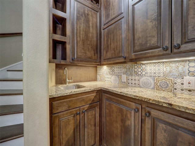 kitchen with dark brown cabinetry, light stone counters, open shelves, and decorative backsplash