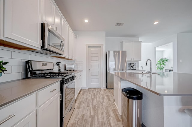 kitchen with visible vents, white cabinets, appliances with stainless steel finishes, light countertops, and a sink