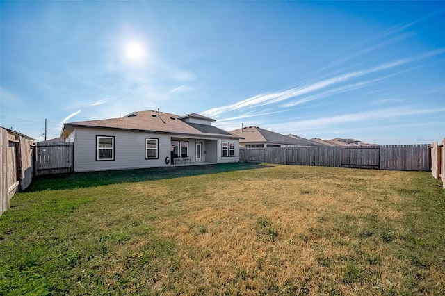 back of property featuring a fenced backyard and a yard