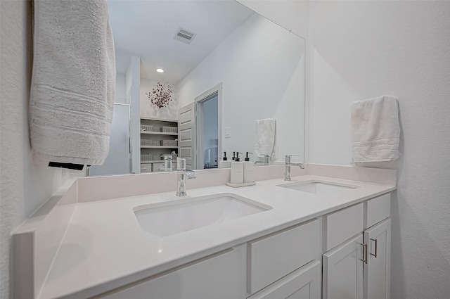 bathroom featuring double vanity, visible vents, a sink, and recessed lighting