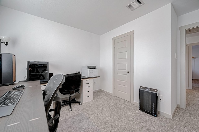 office space featuring light carpet, baseboards, visible vents, and heating unit