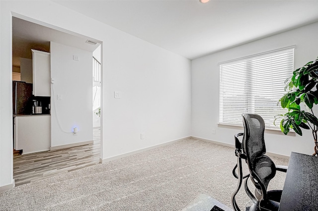 unfurnished office featuring baseboards, visible vents, and light colored carpet