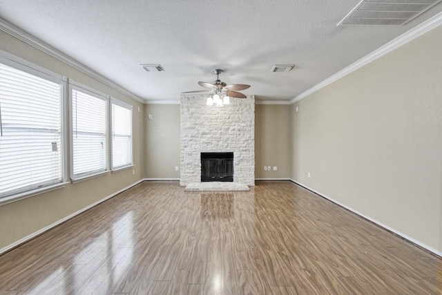 unfurnished living room featuring visible vents, crown molding, a stone fireplace, and wood finished floors