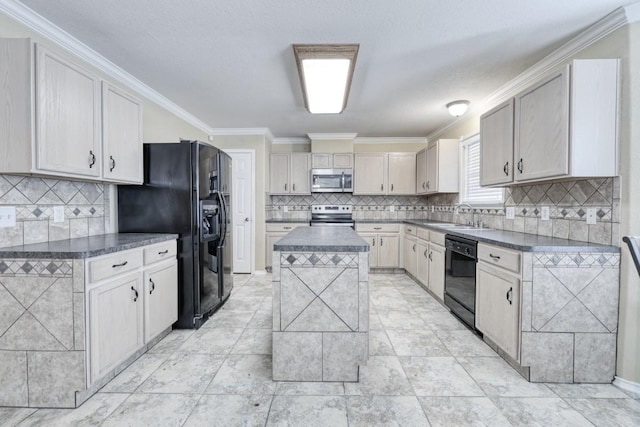 kitchen with dark countertops, ornamental molding, a center island, black appliances, and a sink