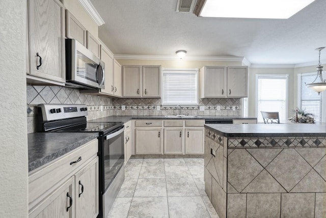 kitchen featuring crown molding, stainless steel appliances, dark countertops, hanging light fixtures, and a sink