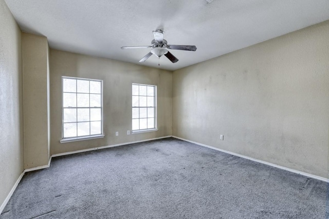 carpeted spare room with ceiling fan, baseboards, and a textured wall