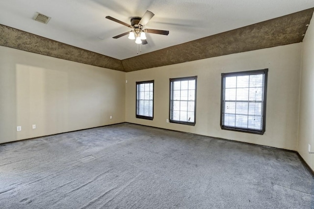 spare room featuring carpet floors, lofted ceiling, visible vents, and ceiling fan