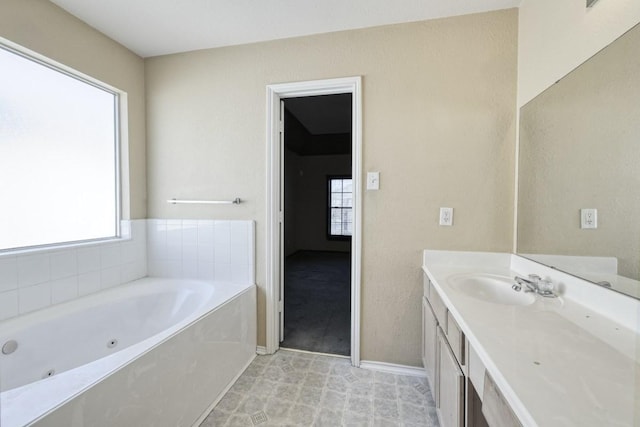 bathroom featuring baseboards, plenty of natural light, vanity, and a whirlpool tub