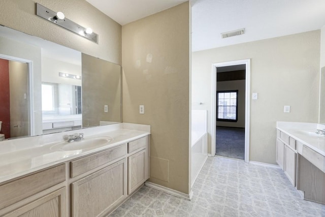 full bathroom featuring a garden tub, two vanities, visible vents, a sink, and baseboards