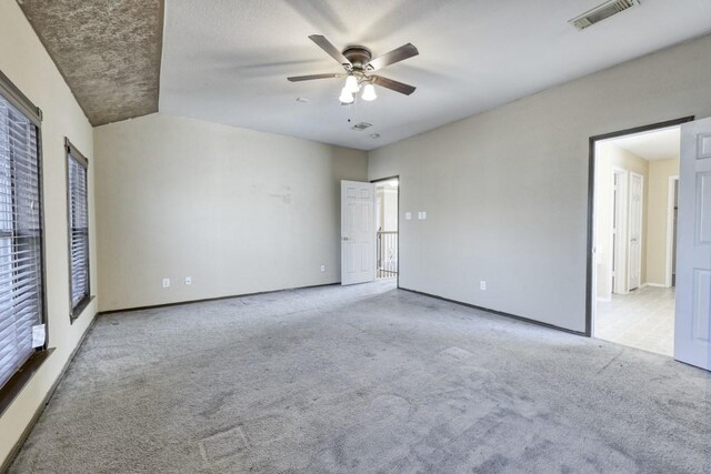 empty room featuring ceiling fan, visible vents, and light colored carpet