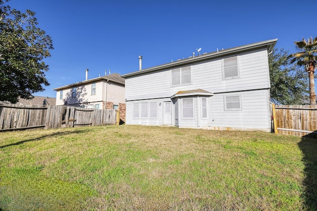 rear view of property featuring fence and a lawn