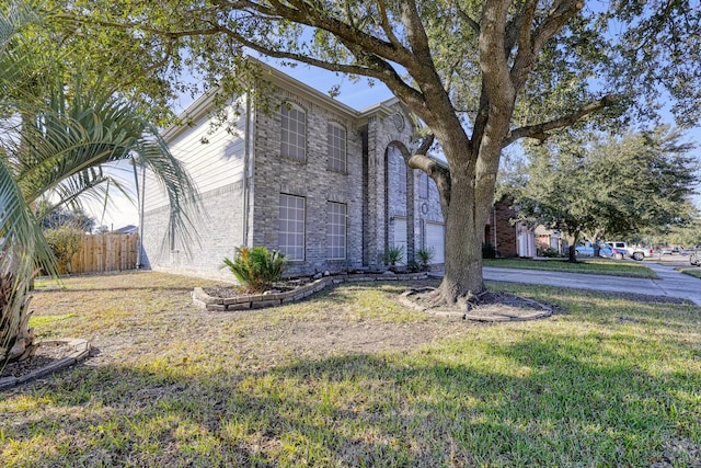 view of front of house featuring a garage, a yard, brick siding, and fence