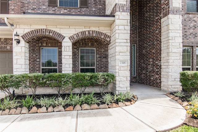 view of exterior entry with stone siding and brick siding