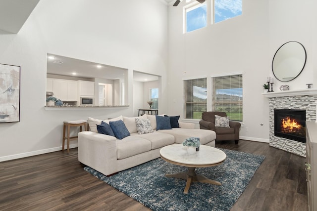 living area featuring dark wood-type flooring, a tile fireplace, and baseboards