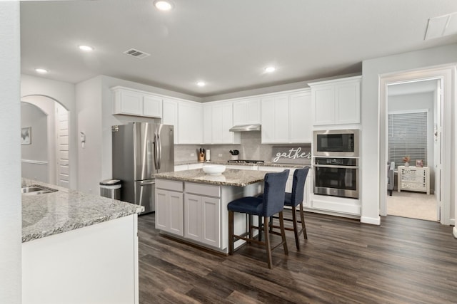 kitchen with light stone countertops, visible vents, appliances with stainless steel finishes, and white cabinets