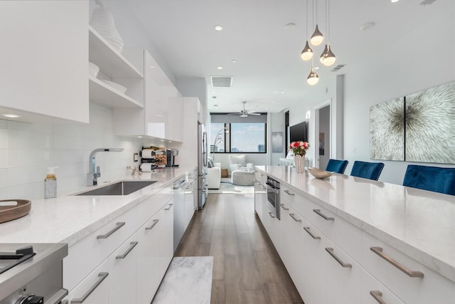 kitchen featuring decorative light fixtures, a breakfast bar area, white cabinets, a sink, and modern cabinets