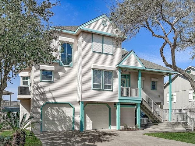 view of front facade with a porch, driveway, an attached garage, and stairs