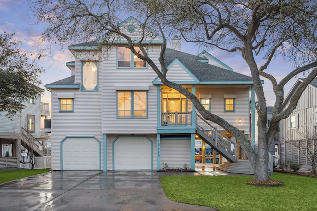 view of front facade featuring driveway, a chimney, stairs, a garage, and a lawn