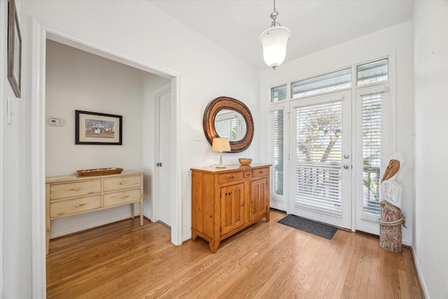 entryway with light wood-type flooring, baseboards, and vaulted ceiling