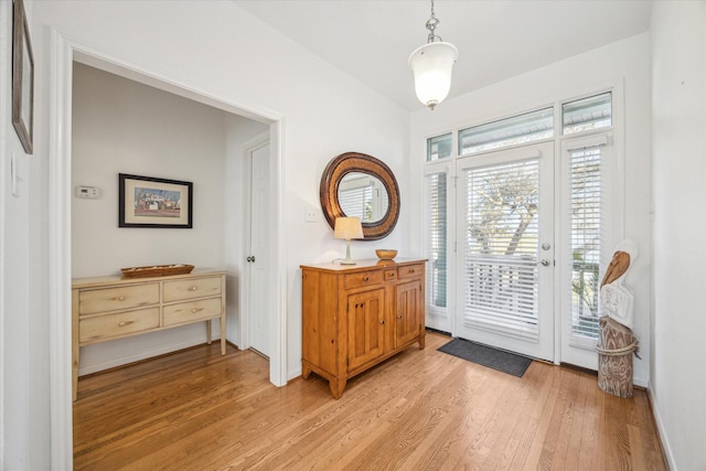entrance foyer featuring baseboards, vaulted ceiling, and light wood-type flooring