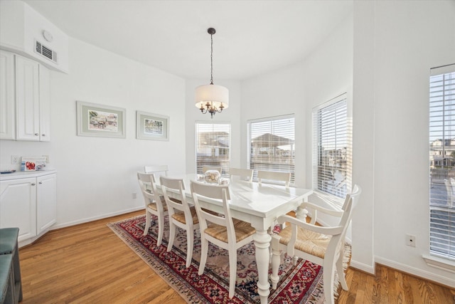 dining room featuring baseboards, visible vents, light wood-style floors, and a chandelier