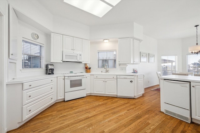 kitchen featuring white appliances, light wood finished floors, a sink, light countertops, and white cabinets