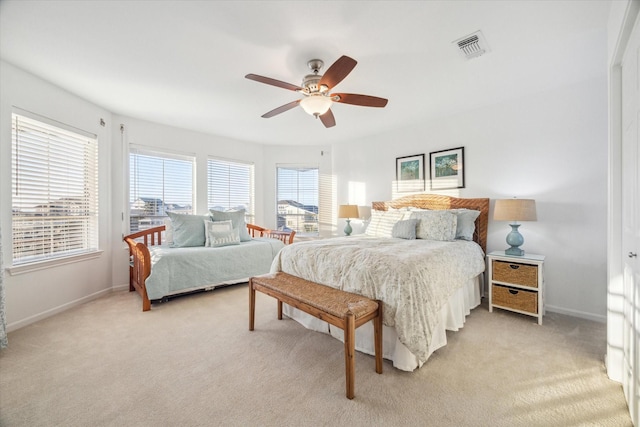 bedroom featuring visible vents, baseboards, light colored carpet, and ceiling fan