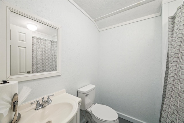 full bath featuring curtained shower, toilet, vaulted ceiling, a textured wall, and vanity