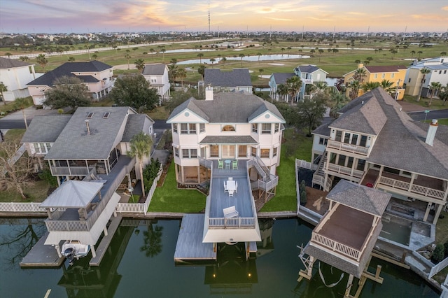 aerial view at dusk featuring a water view and a residential view