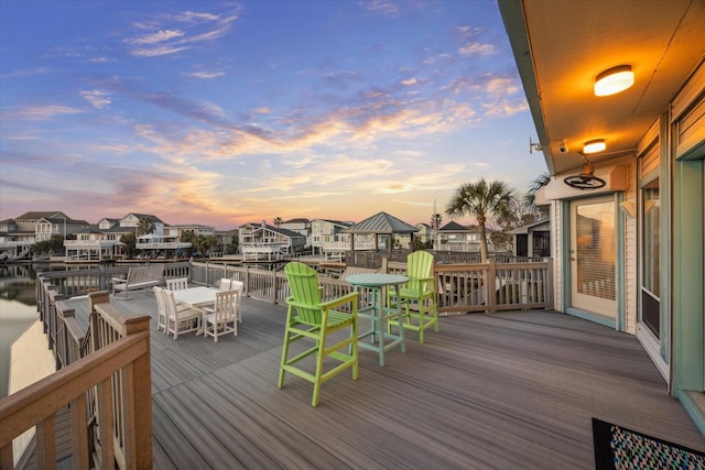 deck at dusk featuring a residential view and outdoor dining space
