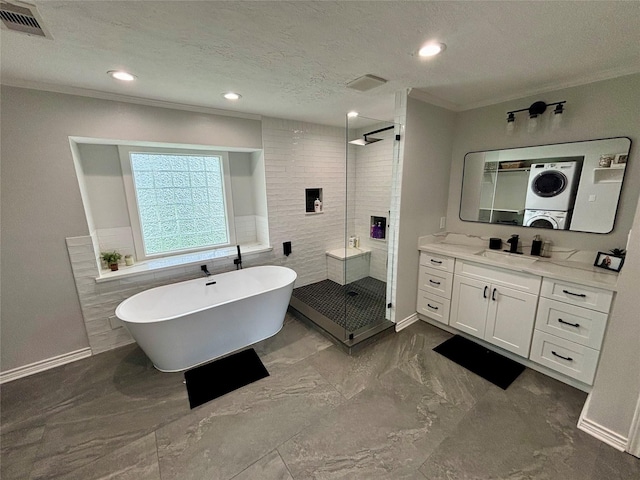 bathroom featuring stacked washer and clothes dryer, visible vents, a freestanding bath, a stall shower, and a textured ceiling