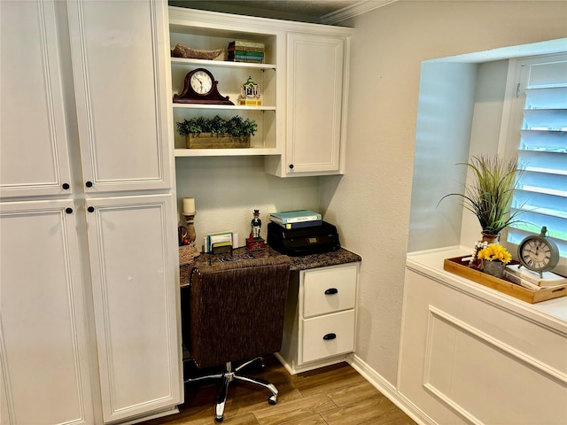 office space with built in desk, light wood-type flooring, and baseboards