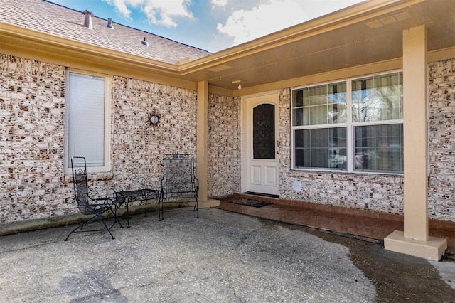 doorway to property featuring a shingled roof and a patio