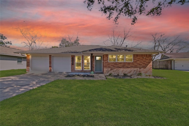 view of front of property with a yard, driveway, brick siding, and an attached garage