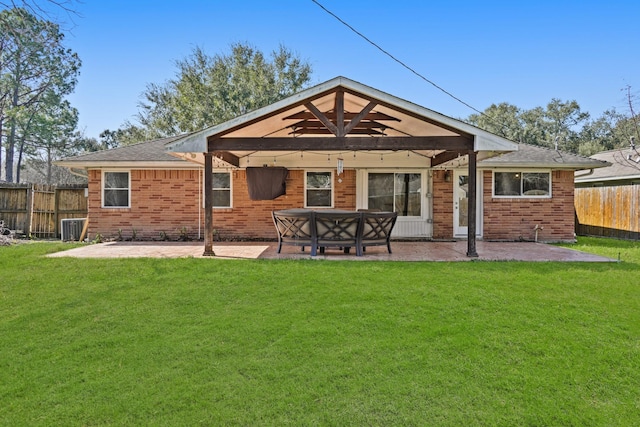 back of house featuring a patio, central AC unit, brick siding, fence, and a yard