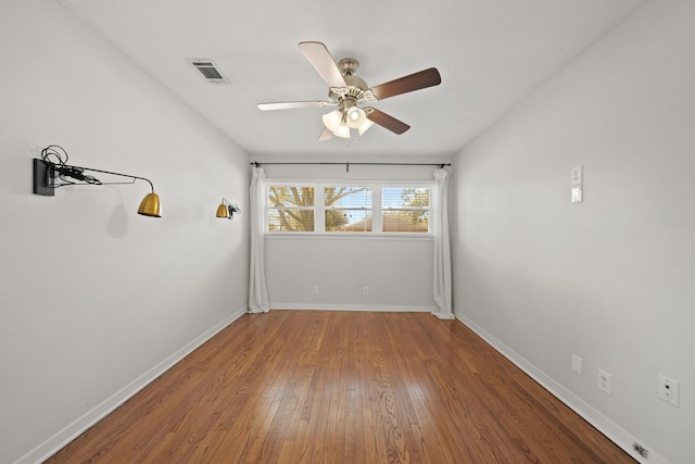 unfurnished room with a ceiling fan, baseboards, visible vents, and wood finished floors