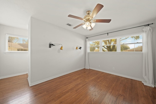 unfurnished room with a ceiling fan, visible vents, baseboards, and wood finished floors