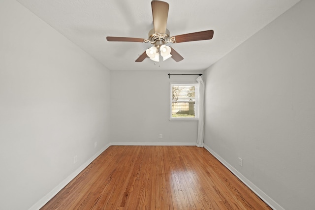 empty room featuring a ceiling fan, light wood-type flooring, and baseboards