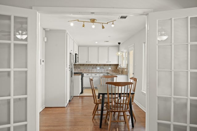 dining space featuring light wood-type flooring and visible vents