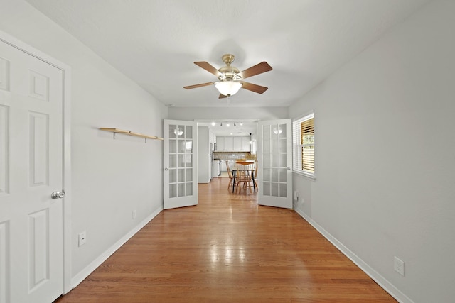 spare room with light wood-style flooring, baseboards, ceiling fan, and french doors