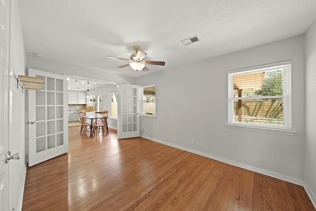 empty room featuring baseboards, visible vents, wood finished floors, and french doors