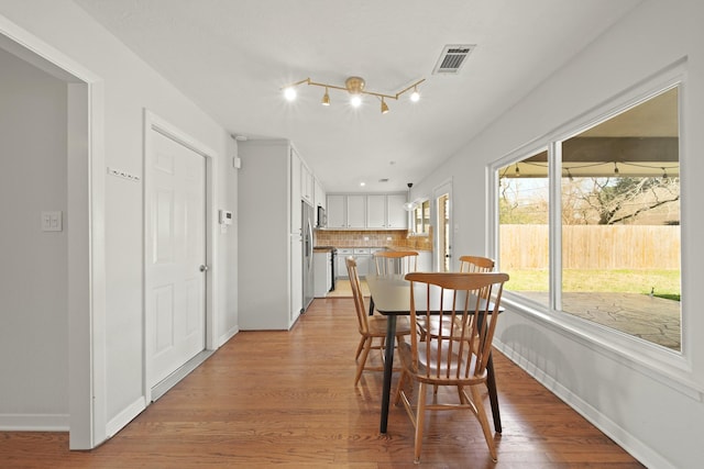 dining area with light wood finished floors, baseboards, and visible vents